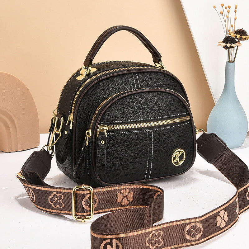 stylish cream and brown crossbody handbag with gold accents and a patterned adjustable strap