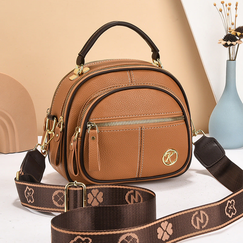 stylish cream and brown crossbody handbag with gold accents and a patterned adjustable strap