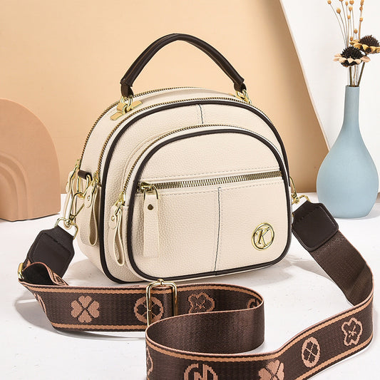stylish cream and brown crossbody handbag with gold accents and a patterned adjustable strap